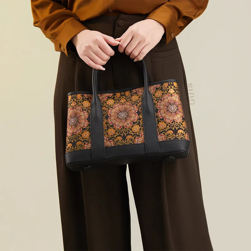 Model standing and holding the top handles of the Luxury Chinoiserie Dayun Brocade Pomegranate Motif Silk Handbag with both hands, front view.