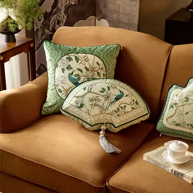 Fan-shaped luxury chinoiserie jade green decorative throw pillow leaning on a sofa.