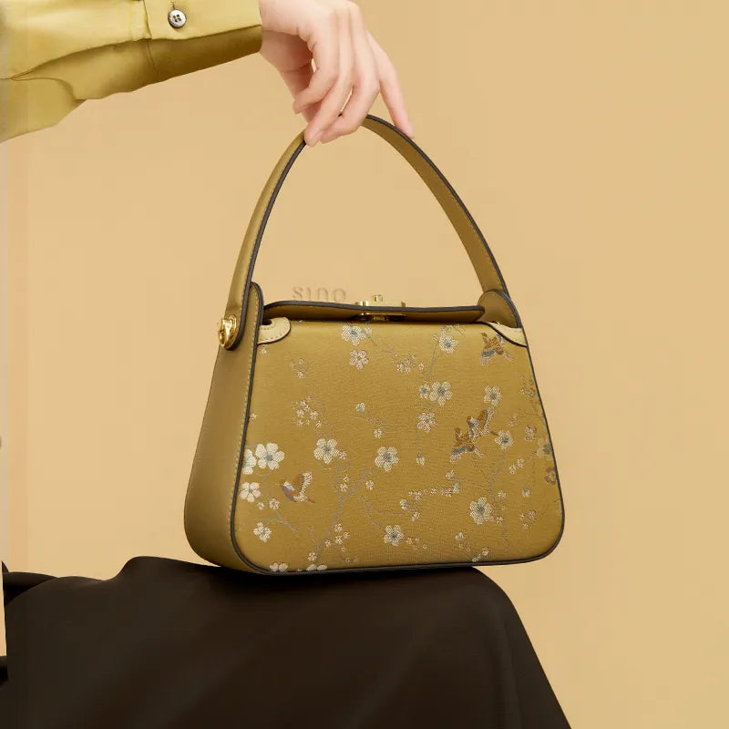 Seated model displaying the Luxury Chinoiserie Song Brocade Magpie & Plum Blossom Handbag on the knees.