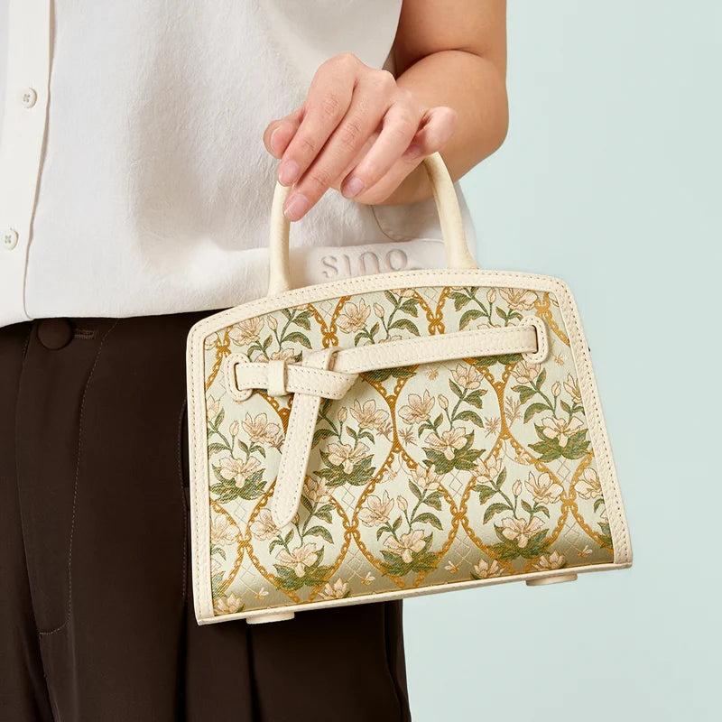 Model hand carrying the Luxury Dayun Brocade Verdant Floral Large Leather Top Handle Bag, highlighting its roomy structured shape.