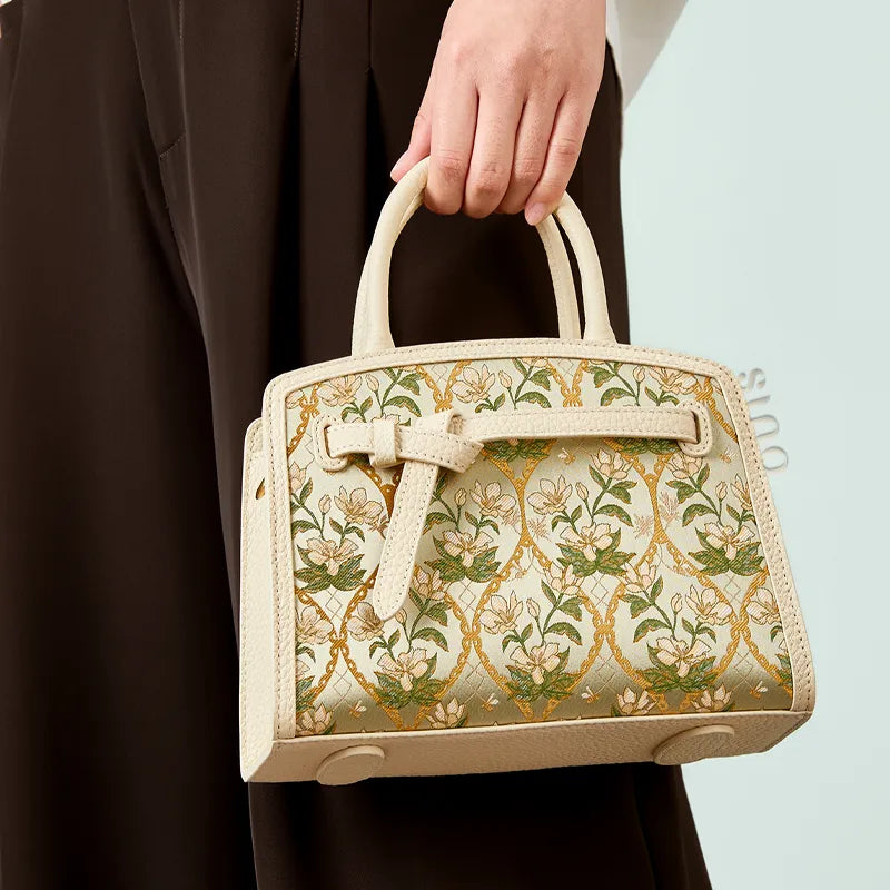 Lifestyle view of the Luxury Dayun Brocade Verdant Floral Large Leather Top Handle Bag featuring ivory leather and floral brocade.