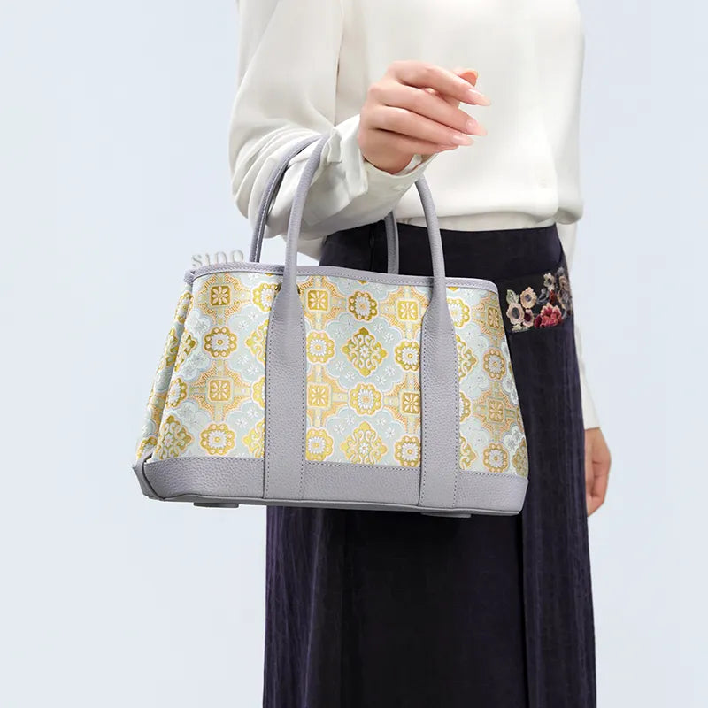 Side view of model carrying the luxury gold-woven Song brocade Ruyi motif tote bag by hand.