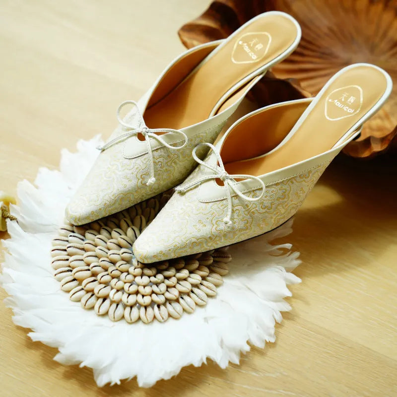 Luxury ivory Song Brocade mule shoes featuring the traditional Ding Sheng auspicious pattern and delicate bow detail.