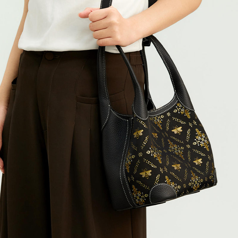 Model carrying the Luxury Shu Brocade Gilded Jade Leather Basket Tote Bag, showing the black leather trim, structured basket tote shape, and gilded motif.