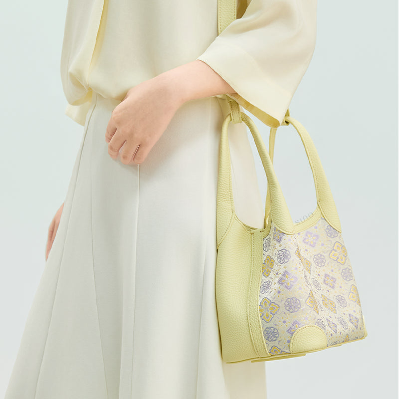 Side model view of the Luxury Shu Brocade Persimmon Calyx Motif Basket Tote Bag, highlighting the soft yellow leather side panel and brocade body.