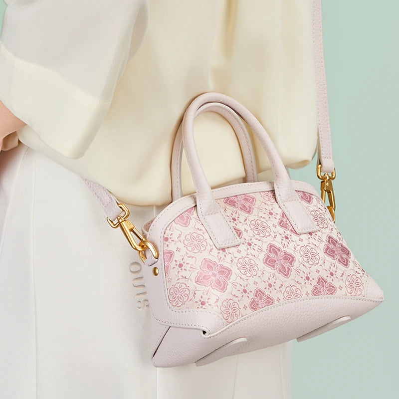 Model wearing the Luxury Shu Brocade Pink Persimmon Calyx Leather Top Handle Bag with detachable shoulder strap.