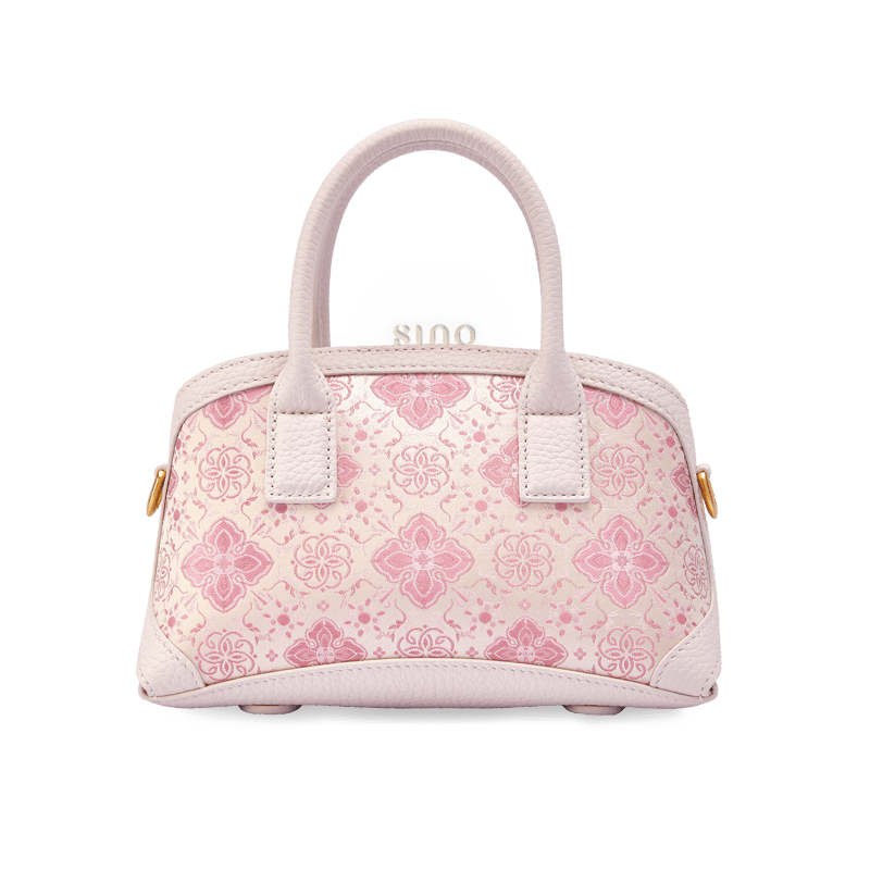 Front view of the Luxury Shu Brocade Pink Persimmon Calyx Leather Top Handle Bag featuring a soft pink brocade pattern and elegant leather trim.