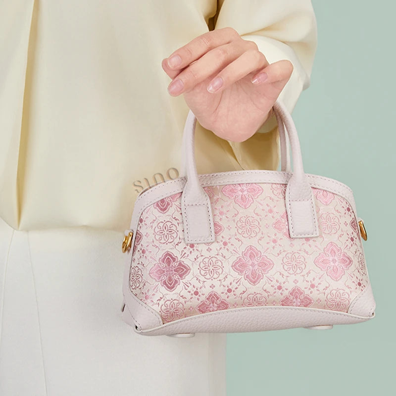 Front lifestyle view of the Luxury Shu Brocade Pink Persimmon Calyx Leather Top Handle Bag carried by hand.