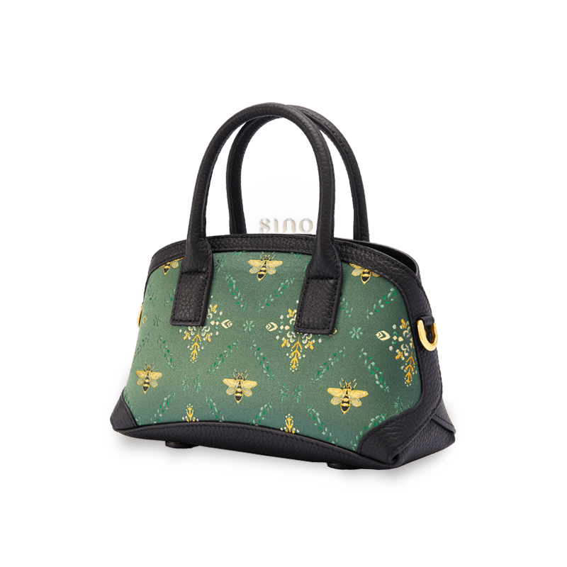 Angled view of the Luxury Shu Brocade Verdant Layers Leather Top Handle Bag showing its structured shape and elegant black leather handles.