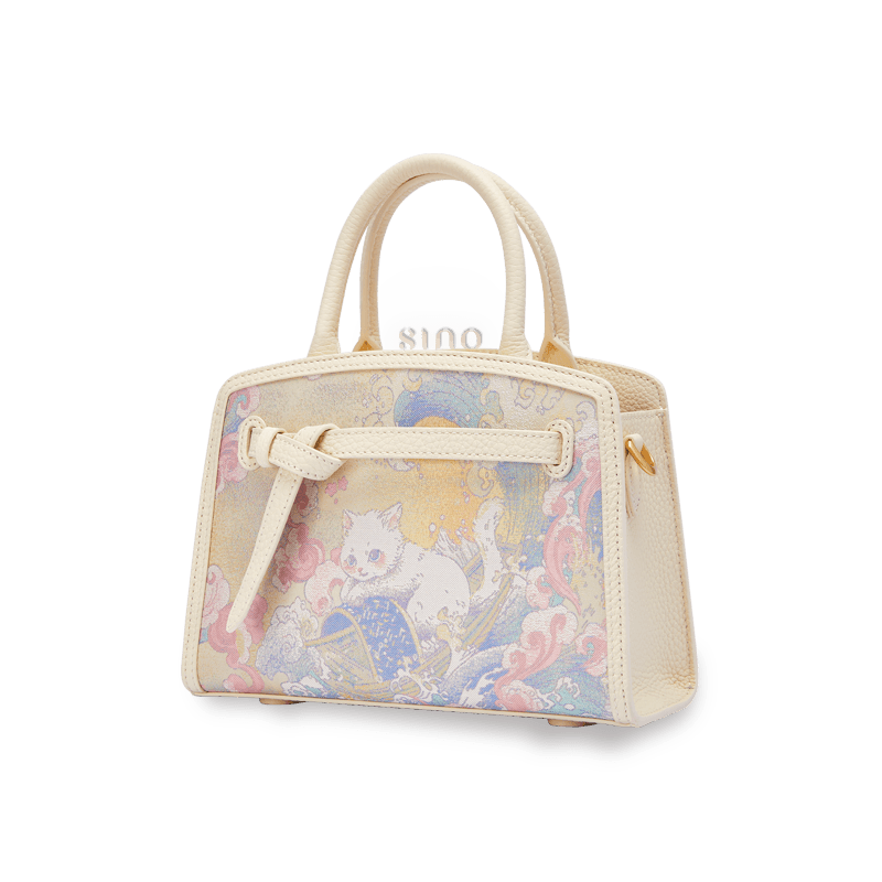 Angled view of the Luxury Song Brocade Brave Voyage Leather Top Handle Bag showing its structured silhouette, double handles, and Chinese brocade panel.