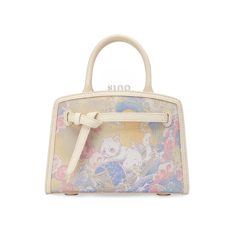 Front view of the Luxury Song Brocade Brave Voyage Leather Top Handle Bag featuring a whimsical cat voyage motif and ivory leather trim.