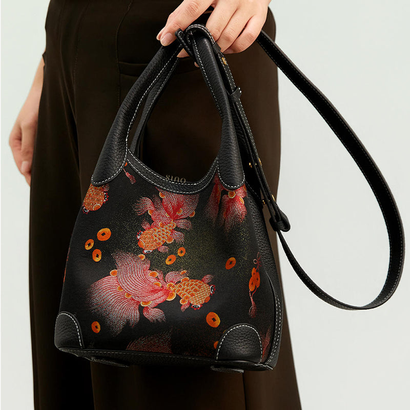 Close-up handheld view of the Chinoiserie Luxury Song Brocade Golden Carp Leather Basket Tote Bag, showing the carp motif, black leather handles, and long strap.