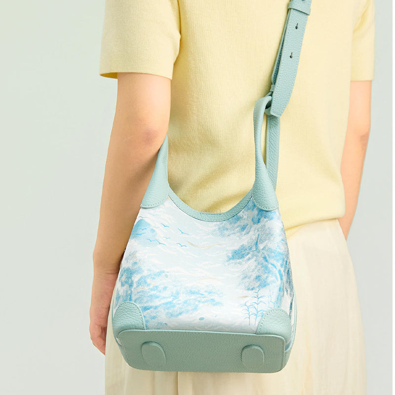 Back model view of the Luxury Song Brocade Misty Mountain Forest Leather Basket Tote Bag, highlighting the landscape brocade design, pale blue leather base, and everyday styling.