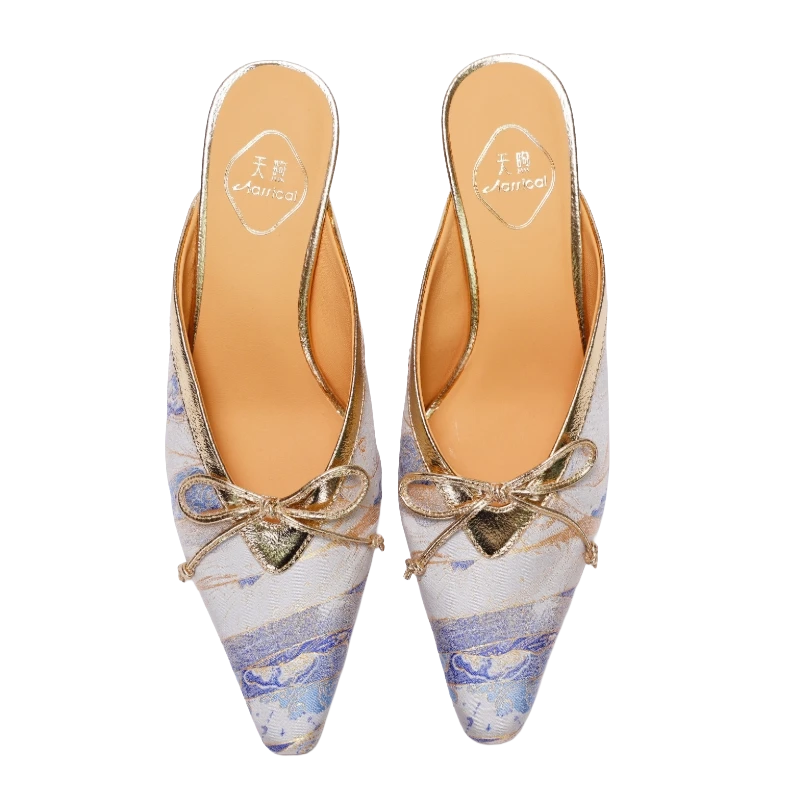 Transparent top view of Luxury Song Brocade Moonlit Splendor kitten heel mules for women featuring ivory brocade fabric, elegant blue and gold patterns, pointed toes, and delicate bow details.