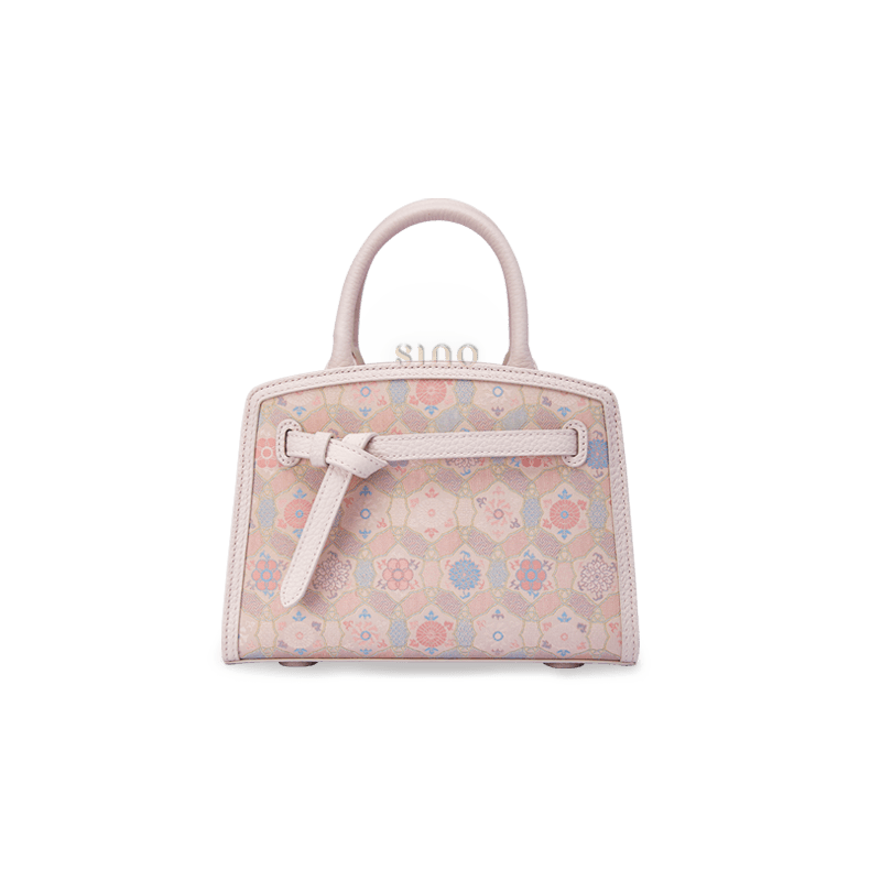 Front view of the Luxury Song Brocade Ruyi Longevity Motif Leather Top Handle Bag, featuring a compact structured shape, soft pink brocade pattern, and leather trim.