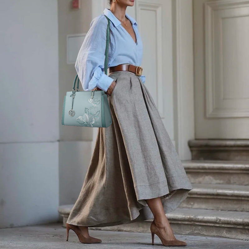 The model is carrying a light blue handbag over one shoulder, decorated with magnolia patterns.