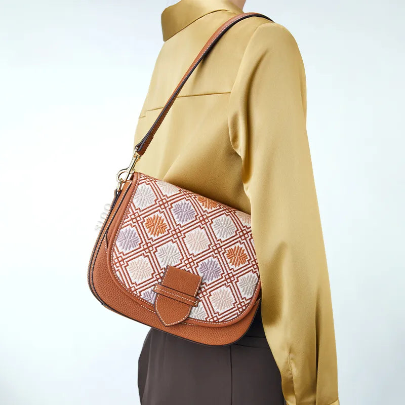 Model wearing zhuang brocade chrysanthemum bag on shoulder.