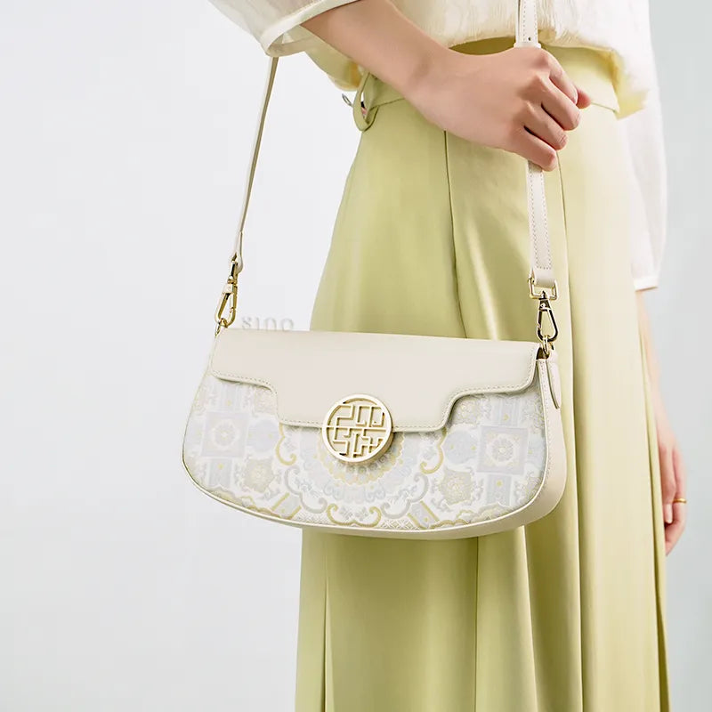 Model carrying white brocade bag on shoulder.