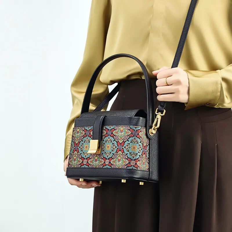 Model wearing crossbody bag with scrolling foliage motif.