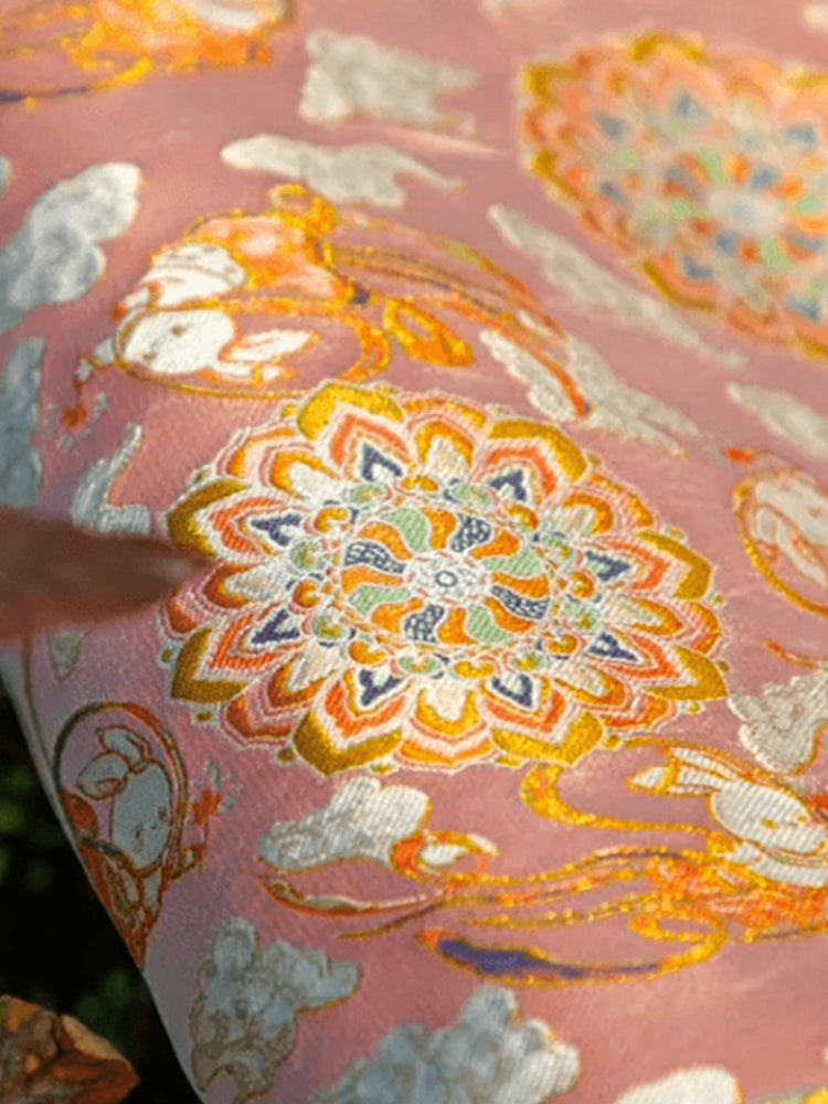 Close-up of pink Nanjing Yun brocade fabric with floral and cloud motifs, showcasing traditional Chinese silk craftsmanship and luxury brocade artistry.