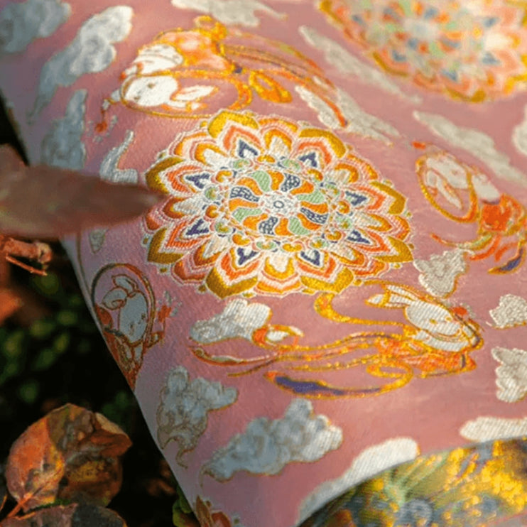 Close-up of pink Nanjing Yun brocade fabric with floral and cloud motifs, showcasing traditional Chinese silk craftsmanship and luxury brocade artistry.