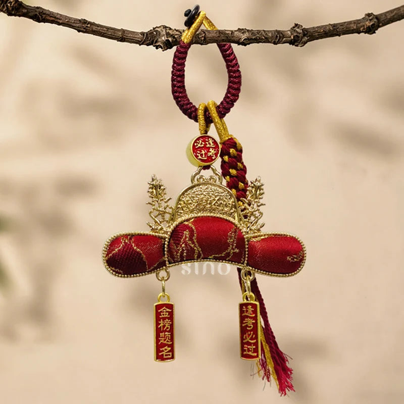 Imperial Scholar Hat bag charm crafted from red Nanjing Yunjin brocade, displayed hanging with gold details and blessing plaques for exam success.