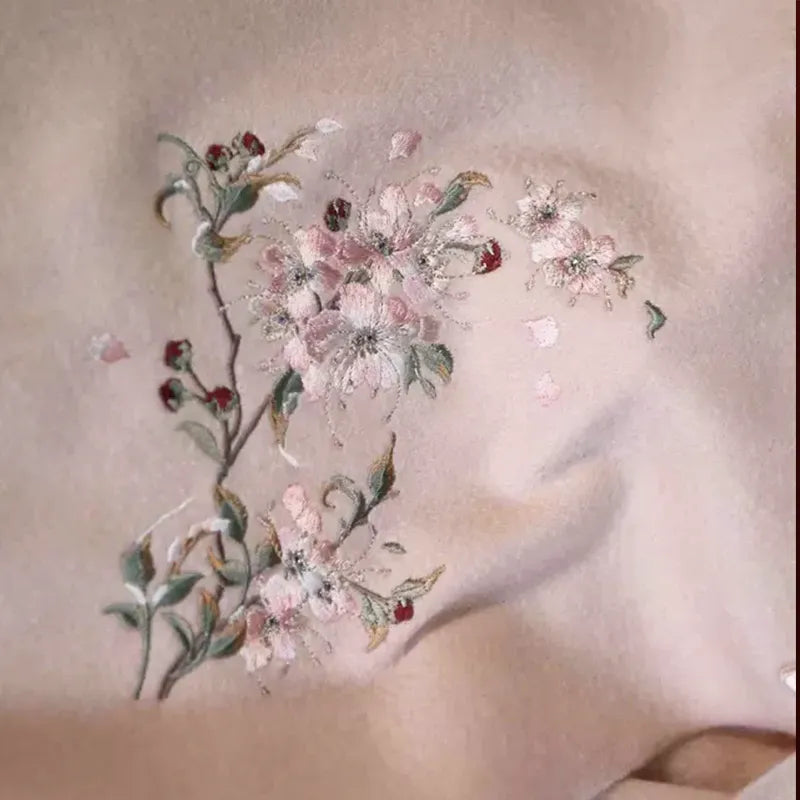 Close-up of hand-stitched plum blossom embroidery on cashmere scarf.