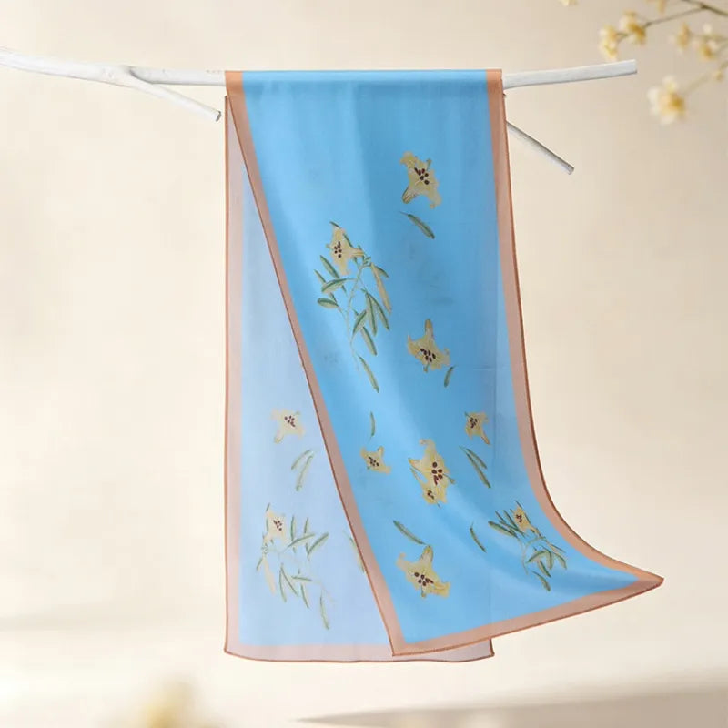 Full view of the Blue Lily Poetic Blossom Mulberry Silk Long Scarf featuring soft blue silk and delicate lily motifs.