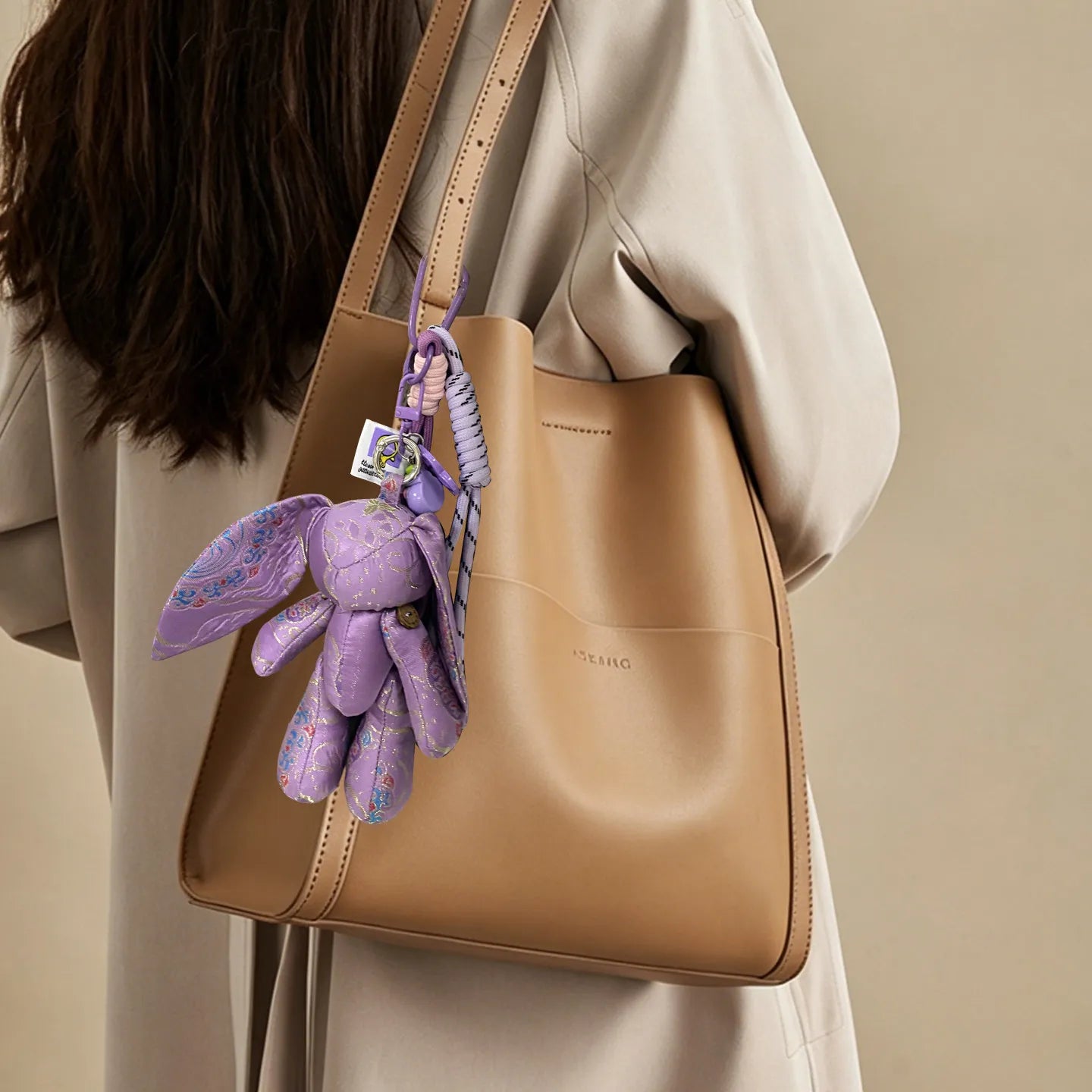 Purple Jade Rabbit Yunjin brocade bag charm attached to a beige tote bag, showing the charm as a Chinese-style accessory for daily use.