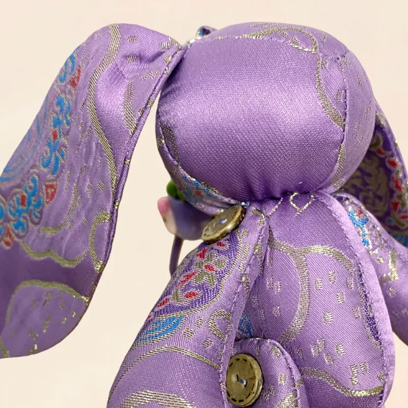 Close-up of the handmade purple Yunjin brocade Jade Rabbit bag charm, showing the woven fabric, stitching, and soft sculpted body details.