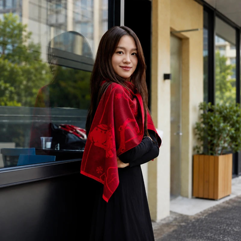 Woman wearing a red mulberry silk scarf over her shoulders for an elegant everyday look outdoors.