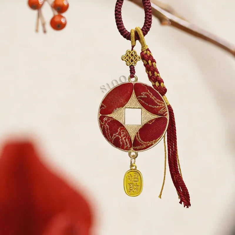 Red Yunjin brocade Chinese coin-shaped bag charm displayed hanging with a square center opening, knotted cord, and gold wealth pendant.