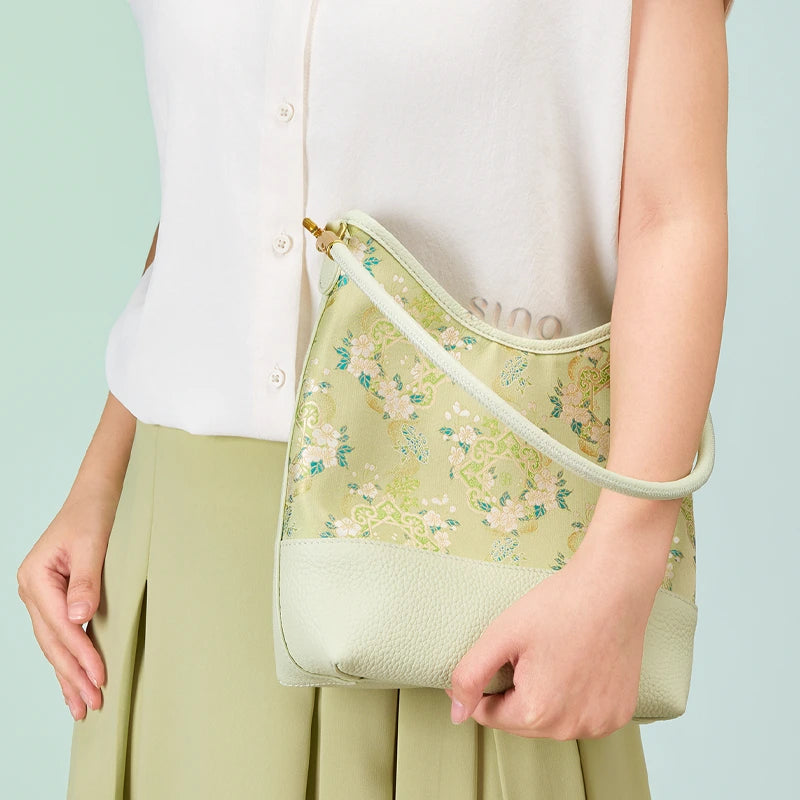 Model holding the Ruyi Blossom Song Brocade leather shoulder bag with a light neutral outfit.