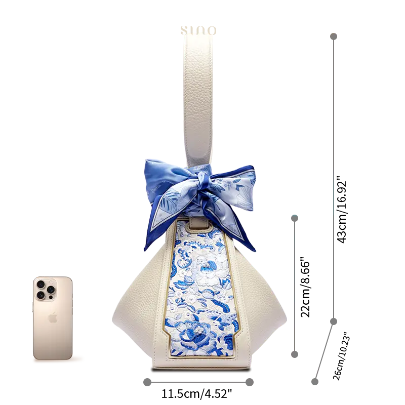 Size comparison of the SANLAN blue floral panel beige leather handbag beside a smartphone.