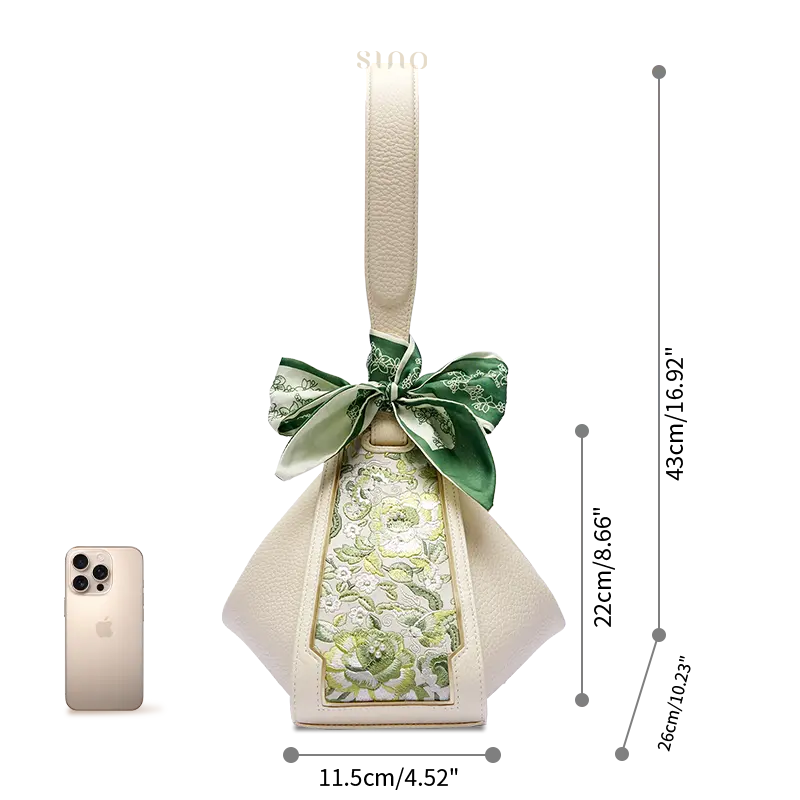 Size comparison of the SANLAN green floral panel beige leather handbag beside a smartphone.