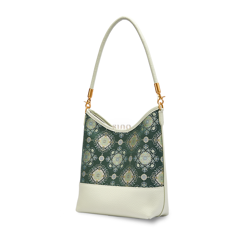 Angled view of a Chinoiserie Emerald Blossom shoulder bag crafted from green Shu Brocade and ivory leather.