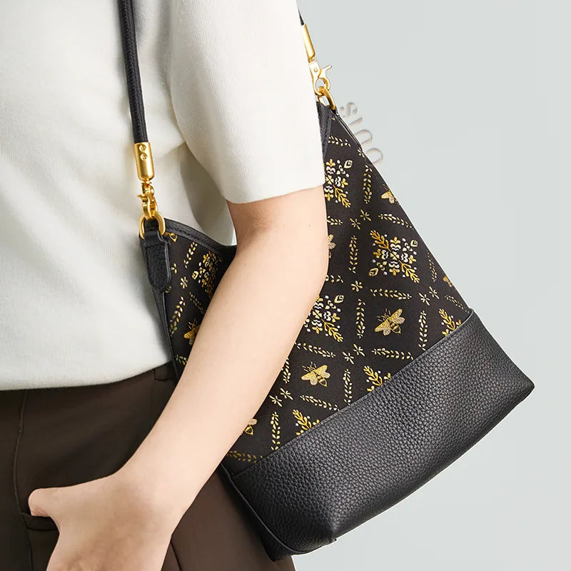 Side view of a model carrying the black Shu Brocade Gilded Jade shoulder bag under the arm.