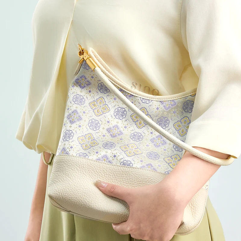 Model holding the ivory Persimmon Calyx Shu Brocade leather shoulder bag with a soft neutral outfit.