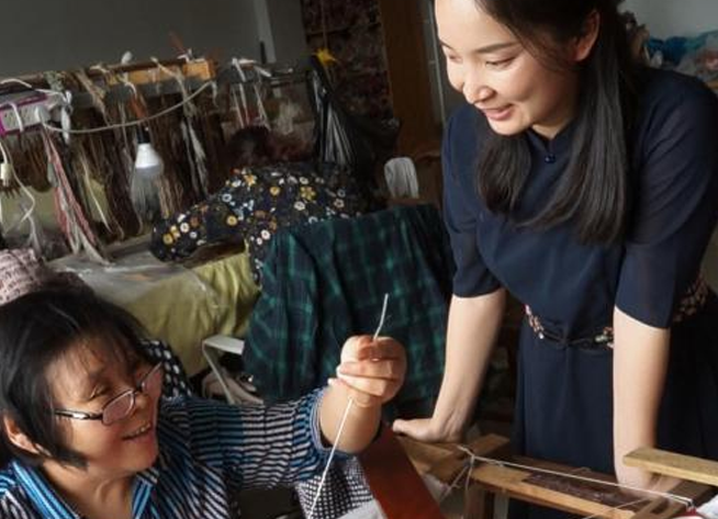 A SinoCultural team member works with a Chinese intangible cultural heritage artisan in a traditional textile workshop, bringing heritage craftsmanship and contemporary design together.