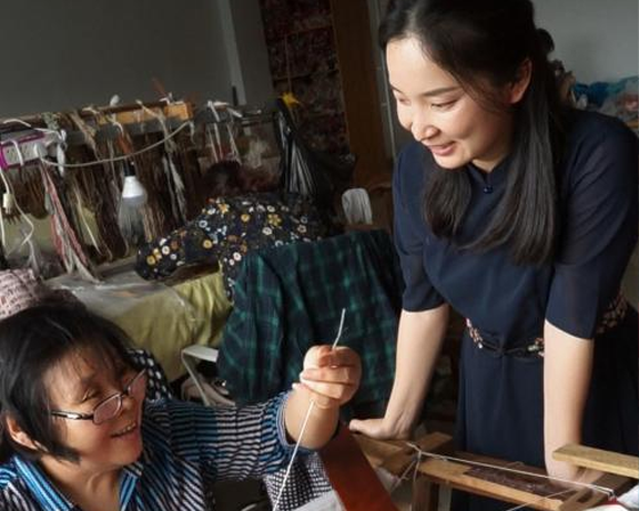 A SinoCultural team member works with a Chinese intangible cultural heritage artisan in a traditional textile workshop, bringing heritage craftsmanship and contemporary design together.