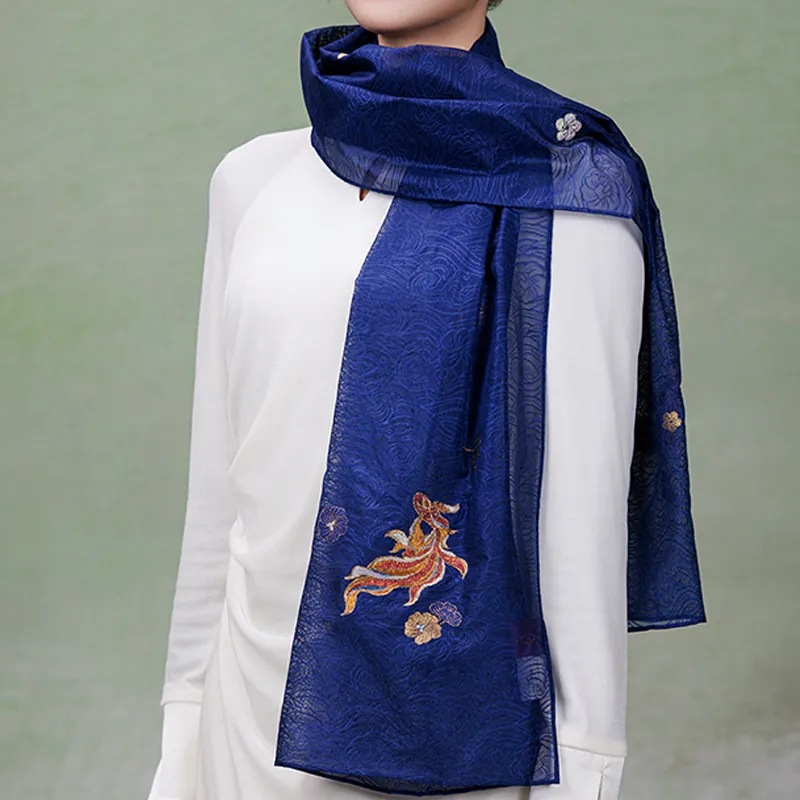 Nanjing Yunjin mulberry silk shawl styled in a layered neck wrap with a white outfit, revealing its semi-sheer patterned border and fish design.