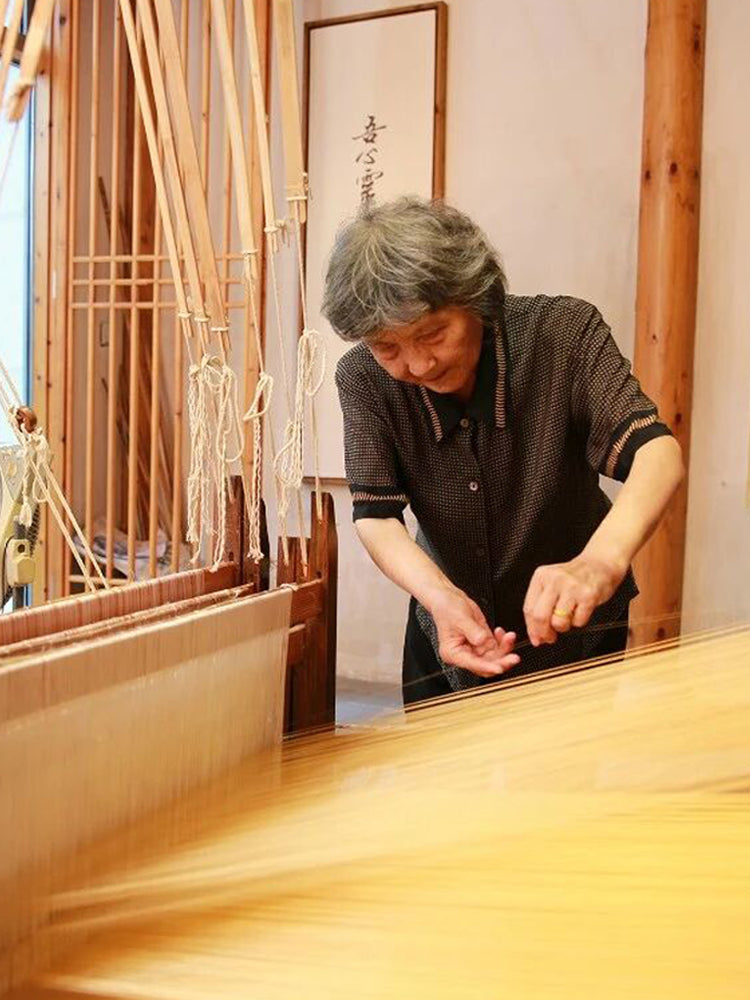 Chinese Song Brocade master Qian Xiaoping weaving silk on a traditional loom in Suzhou, preserving intangible cultural heritage.