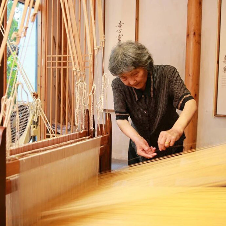 Chinese Song Brocade master Qian Xiaoping weaving silk on a traditional loom in Suzhou, preserving intangible cultural heritage.