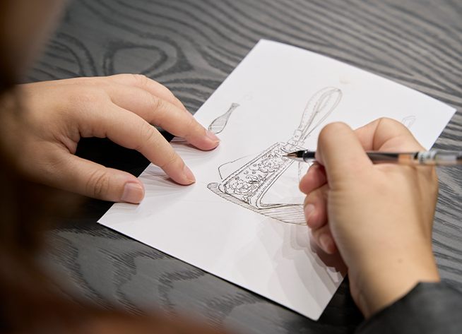 A SinoCultural designer sketches the original Zongzi Convertible Bag with SANLAN embroidery details.