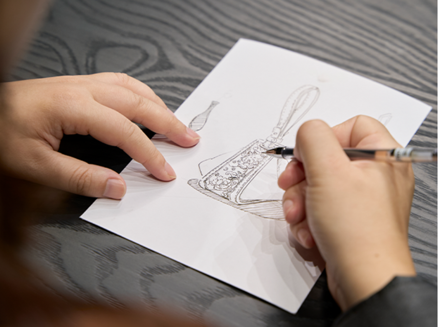 A SinoCultural designer sketches the original Zongzi Convertible Bag with SANLAN embroidery details.