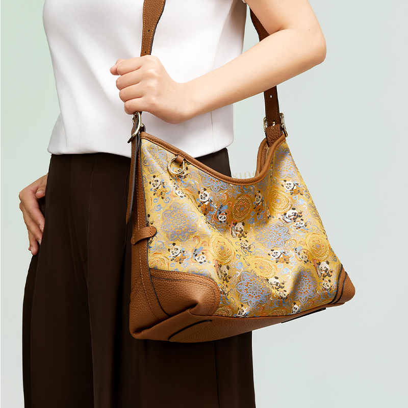 Model carrying the Song Brocade Chang’an Court Dance Leather Crossbody Bag, showing the golden brocade pattern and brown leather shoulder strap.
