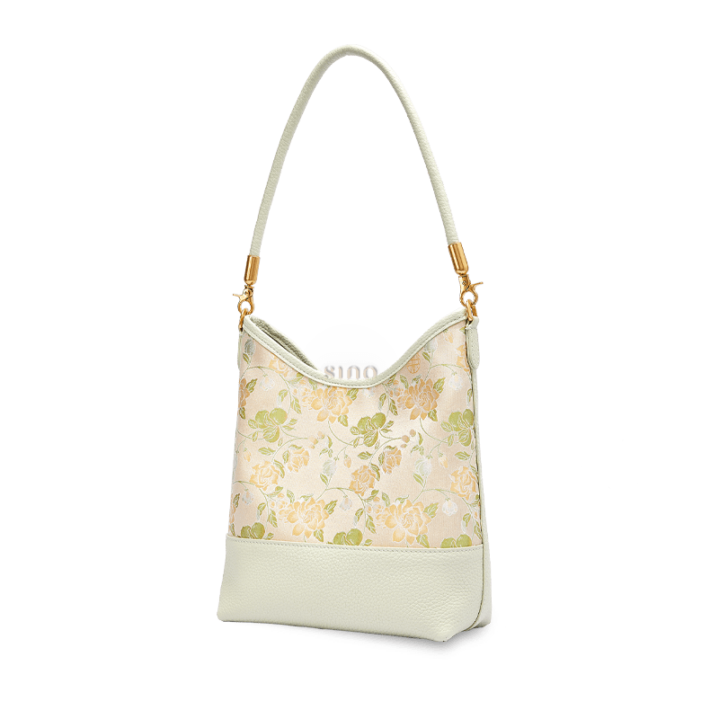 Angled view of a Chinoiserie Jasmine Green Plum shoulder bag crafted from Song Brocade and pale green leather.