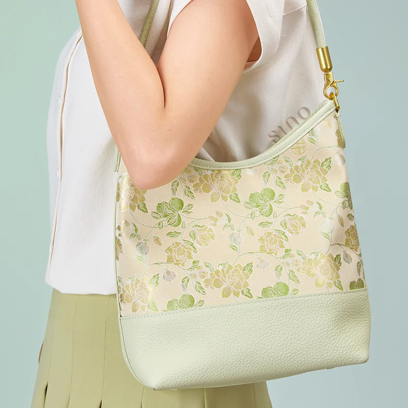 Model carrying the pale green Jasmine Green Plum leather shoulder bag under the arm.