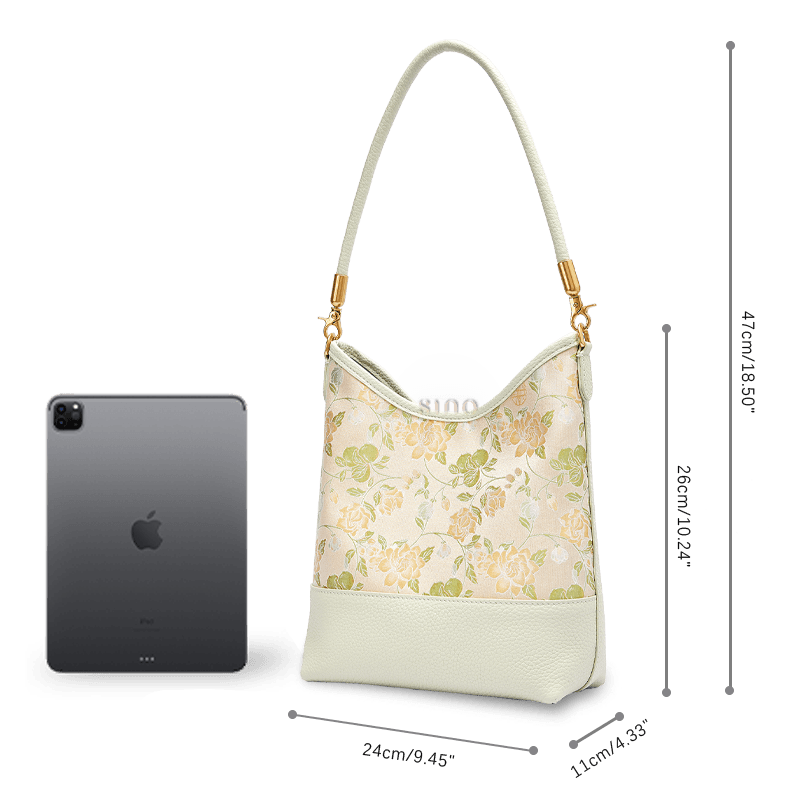 Size and capacity comparison of the Jasmine Green Plum leather shoulder bag beside a tablet.