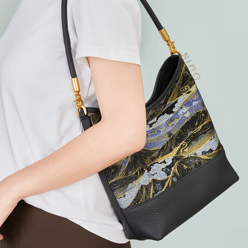 Side view of a model carrying the blue and gold Moonlit Splendor leather shoulder bag.